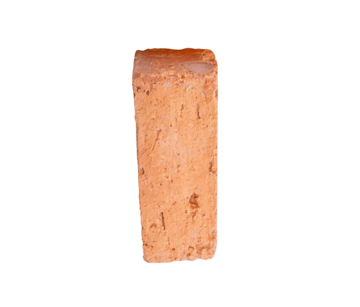 Single red clay brick standing vertically on white background