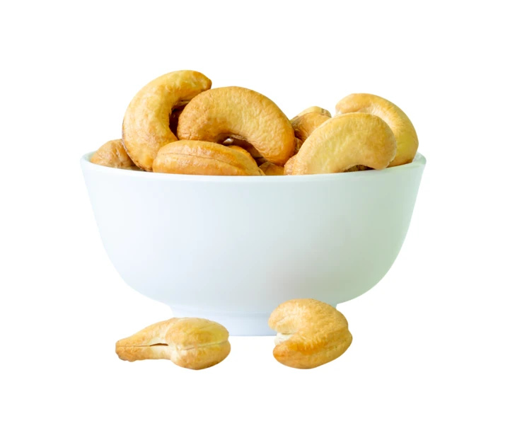 Roasted cashew nuts in a white bowl isolated on white