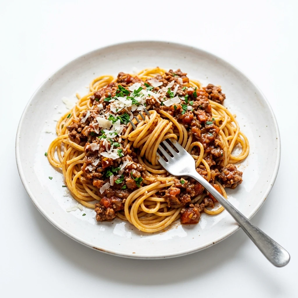 Classic spaghetti bolognese with parmesan and parsley on white plate