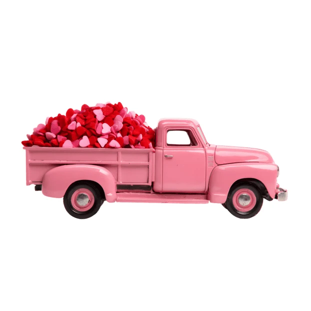 Pink toy pickup truck filled with heart candies on white