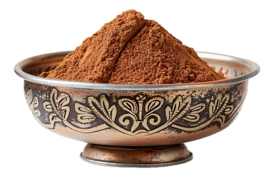 Heap of cocoa powder in an ornate copper bowl