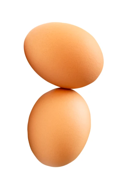 Two brown eggs balanced vertically on white background