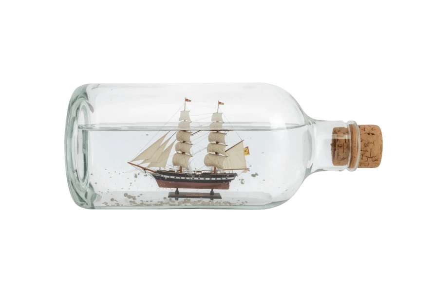 Miniature wooden sailing ship inside a glass bottle