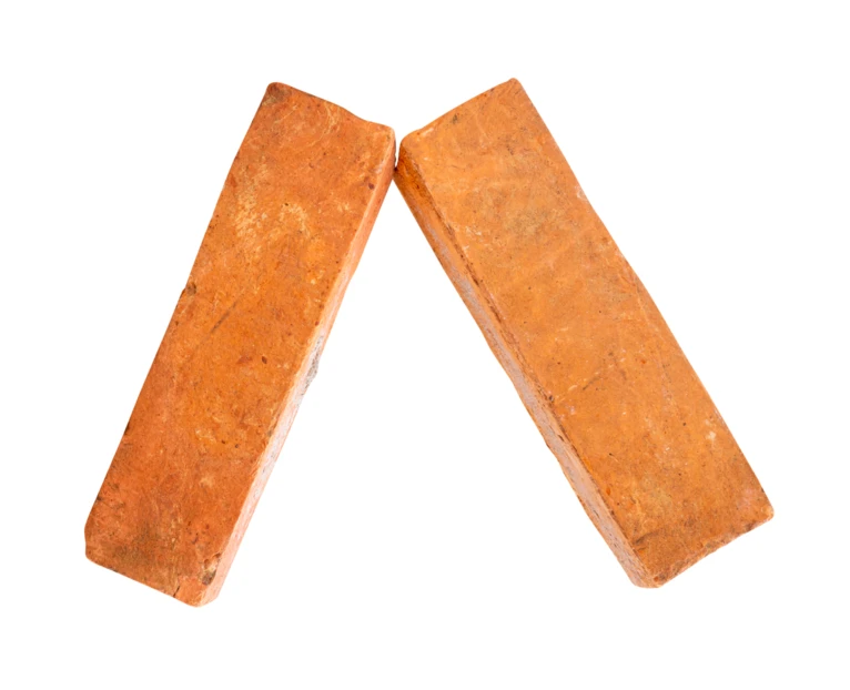Two red clay bricks leaning together on white background